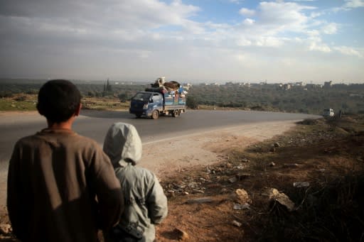 Syrian families flee along a road near the village of al-Mastumah, south of Idlib, on December 24, 2019