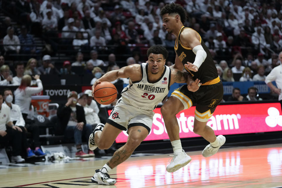 San Diego State guard Matt Bradley (20) drives towards the basket as Wyoming guard Brendan Wenzel defends during the second half of an NCAA college basketball game Saturday, March 4, 2023, in San Diego. (AP Photo/Gregory Bull)