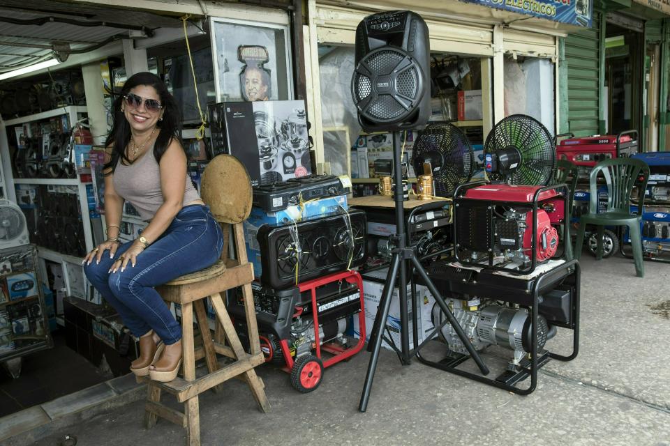 In this May 23, 2019 photo, power generator vendor Juli Barbosa poses for a photo while waiting for customers at the Maracaibo flea market, in Venezuela. The ongoing black outs have led to a scramble for generators by residents and small businesses fearing another big outage could hit without warning, plunging their lives once again into chaos. (AP Photo/Rodrigo Abd)