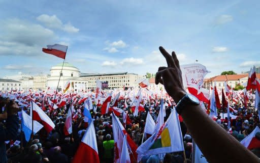 Demonstrators hold Polish national flags during an opposition rally in Warsaw