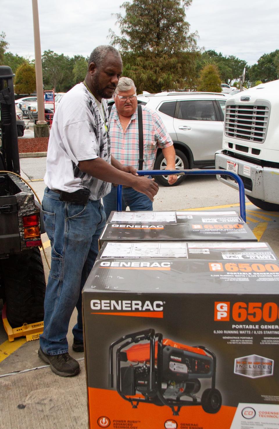 Jamel Broussard, front, and David Boulac wheel out portable generators that each of them bought Tuesday morning at a Lowe's store in Lakeland. Shoppers stood in a long line to purchase the generators.