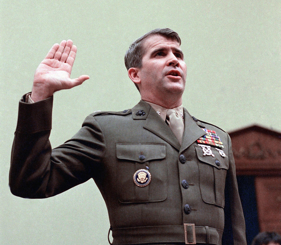 Lt. Col. Oliver North, in Army uniform with rows of badges, raises his right hand.