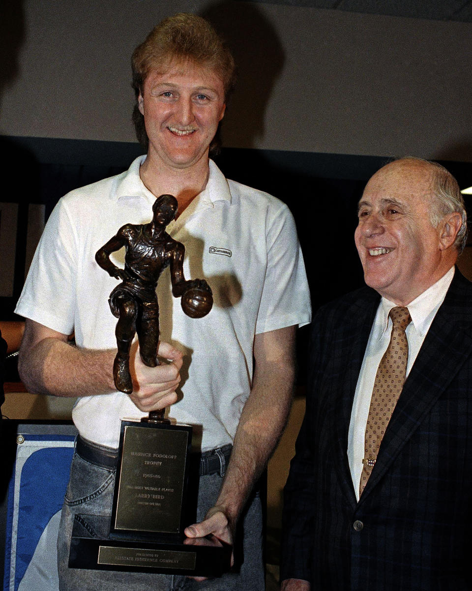 FILE - Boston Celtics' Larry Bird, left, holds the Maurice Podoloff Trophy after being named the NBA's Most Valuable Player for the third consecutive year in Boston, May 29, 1986, while Celtics President Red Auerbach, right, looks on. The trophy carried Podoloff's name for about 60 years, and has now been reimagined and renamed for former NBA basketball player Michael Jordan. (AP Photo/Elise F. Amendola, File)
