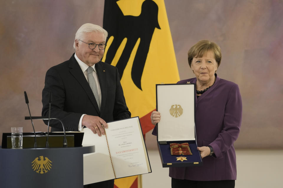 German President Frank-Walter Steinmeier, left, presents the Grand Cross of the Order of Merit of the Federal Republic of Germany in a special design to former Chancellor Angela Merkel, right, during a reception at Bellevue Palace in Berlin, Germany, Monday, April 17, 2023. (AP Photo/Markus Schreiber)