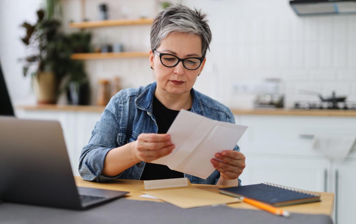 Upset mature woman reading house eviction notice.