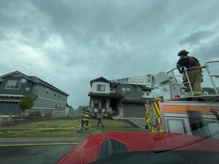 Fire crews respond to a house fire under dark afternoon storm clouds