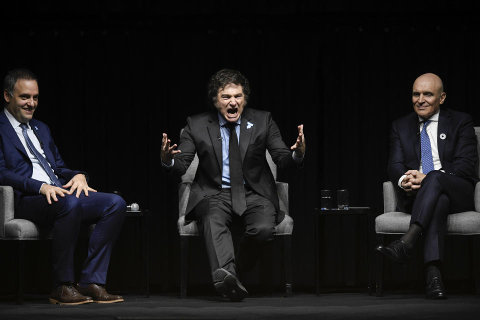 Argentine President Javier Milei, center, gestures to the crowd at a promotional event for his new book, alongside National Deputy Jose Luis Espert, right, and presidential spokesperson Manuel Adorni in Buenos Aires, Argentina, Wednesday, May 22, 2024. (AP Photo/Gustavo Garello)