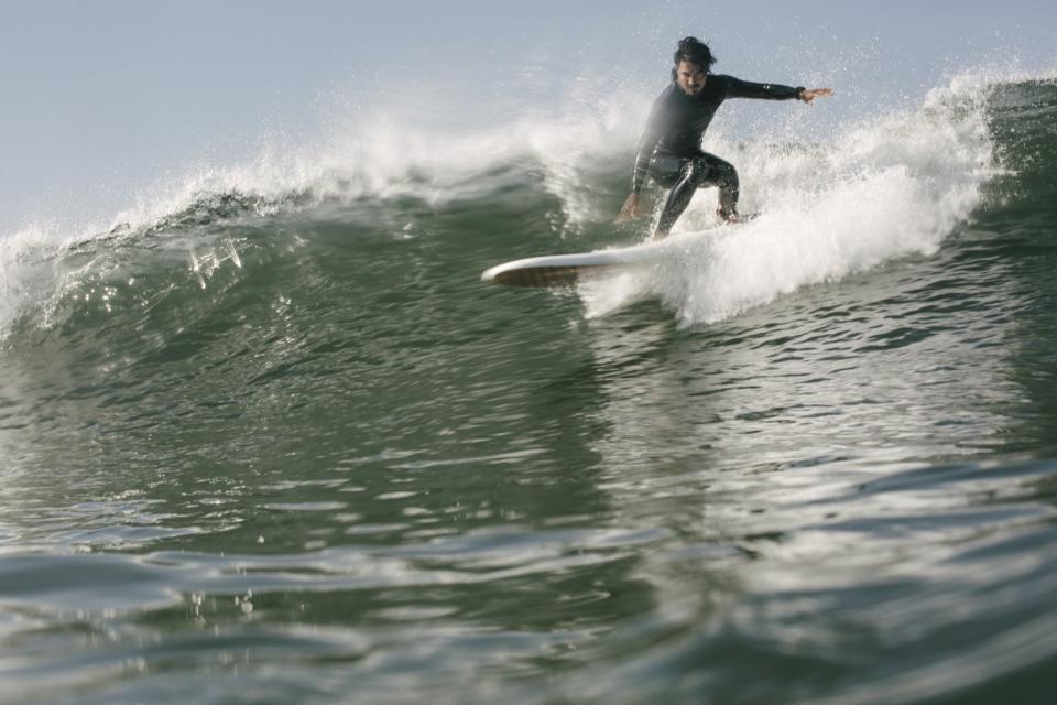 David Malana slides into a wave of a finless surfboard during a morning surf session on Saturday, March 13, 2021.