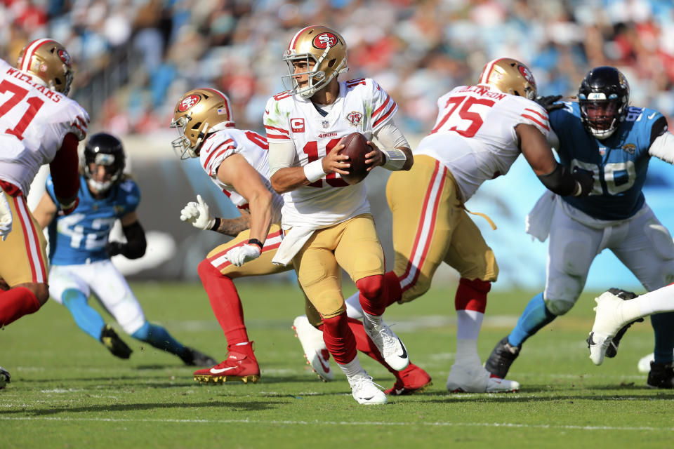 San Francisco 49ers quarterback Jimmy Garoppolo (10) rolls out on a play as Jacksonville Jaguars safety Andrew Wingard, left, and defensive tackle Malcom Brown (90) rush during the second half of an NFL football game, Sunday, Nov. 21, 2021, in Jacksonville, Fla. (AP Photo/Matt Stamey)