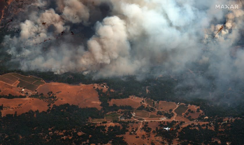 An air tanker, bottom right, flights near active fire lines of the Caldor Fire