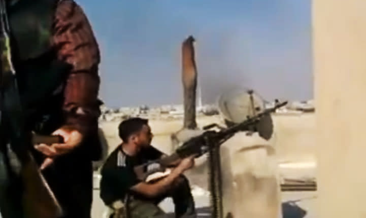 In this image made from amateur video released by the Ugarit News and accessed Tuesday, July 24, 2012, a Free Syrian Army solider fires his weapon during clashes with Syrian government troops in Aleppo, Syria. Turkey sealed its border with Syria to trucks on Wednesday, July 25, 2012 cutting off a vital supply line to the embattled nation as fighting stretched into its fifth day in the commercial capital of Aleppo. (AP Photo/Ugarit News via AP video) TV OUT, THE ASSOCIATED PRESS CANNOT INDEPENDENTLY VERIFY THE CONTENT, DATE, LOCATION OR AUTHENTICITY OF THIS MATERIAL