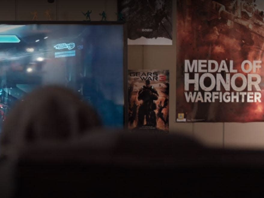 Augustus's bedroom with a television playing a video game and game posters on the walls.
