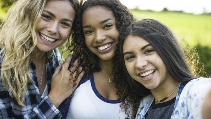 three teenaged girls take a selfie together, smiling