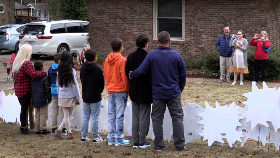 Standing behind a sign that reads “It’s Adoption Day,” Angela and Elliott Turbeville pose for a family photograph with the six children they adopted Monday. The Turbevilles surprised the children on Dec. 20 with the news they would be going to court that afternoon to finalize the adoption.