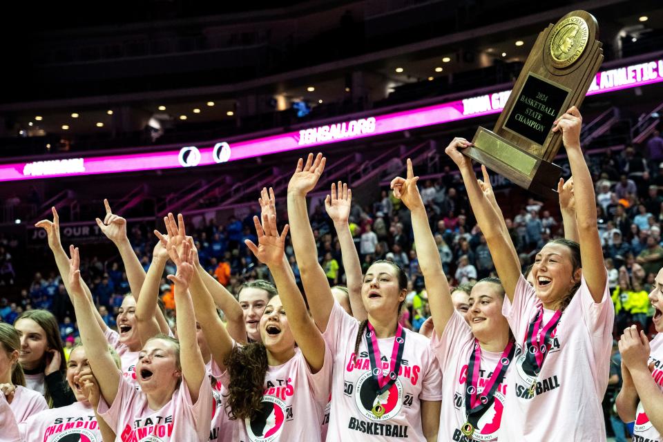 Dike-New Hartford players wave to fans with their 2A state title trophy following their state title game win on Saturday.