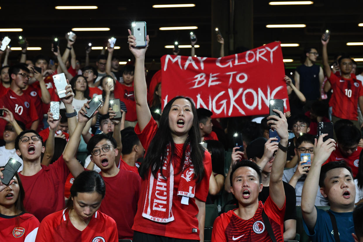 HONG KONG, CHINA - SEPTEMBER 10: Football fans hold up their phones and shout during a protest at the end of the World Cup qualifying match between Hong Kong and Iran at Hong Kong Stadium on September 10, 2019 in Hong Kong, China. Pro-democracy protesters have continued demonstrations across Hong Kong despite the withdrawal of a controversial extradition bill as demonstrators call for the city's Chief Executive Carrie Lam to immediately meet the rest of their demands, including an independent inquiry into police brutality, the retraction of the word 'riot' to describe the rallies, and the right for Hong Kong people to vote for their own leaders. (Photo by Carl Court/Getty Images)