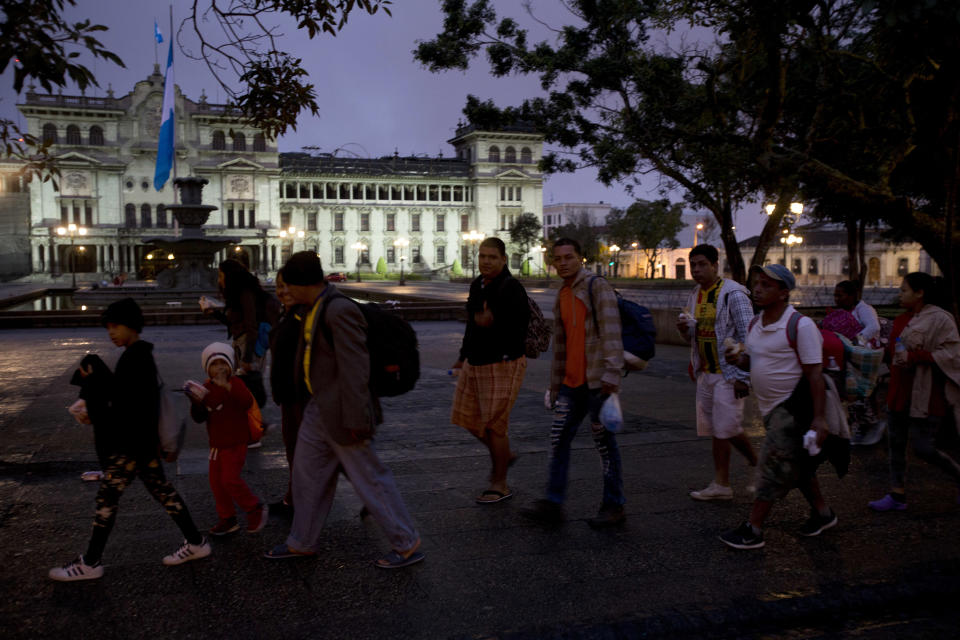 Honduran migrants walk past the National Palace as they leave Guatemala City at sunrise Thursday, Oct. 18, 2018 as they make continue their way north toward the U.S. Many of the more than 2,000 Hondurans in a migrant caravan trying to wend its way to the United States left spontaneously with little more than the clothes on their backs and what they could quickly throw into backpacks. (AP Photo/Moises Castillo)