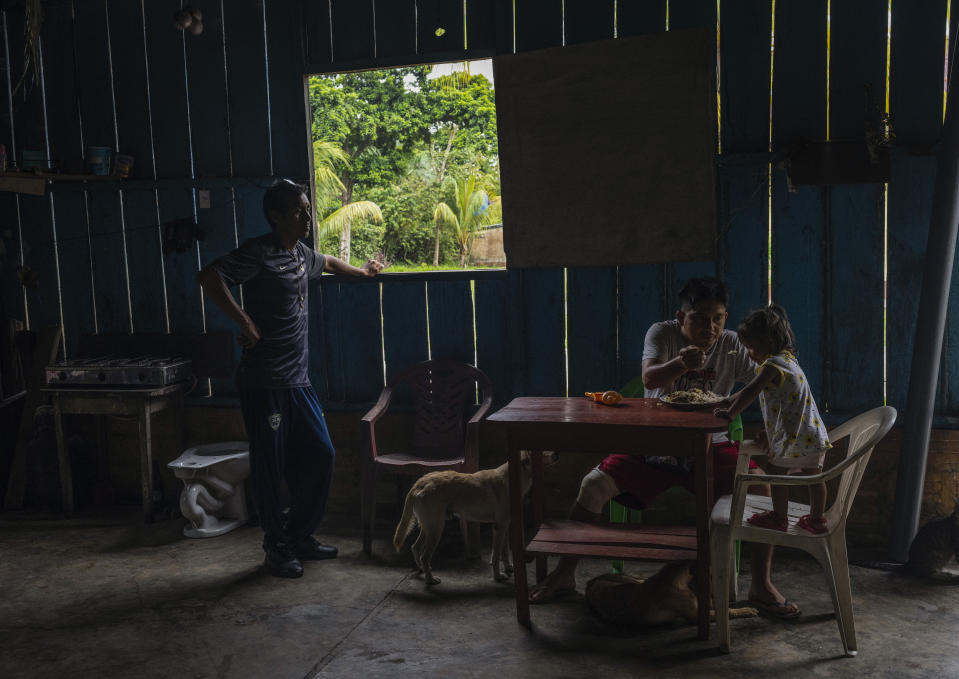 Murui Indigenous Gino Pinedo feeds a spoonful of rice to his 1-year-old daughter Camila, inside their home, in Nuevo Arenal, Peru, Tuesday, May 28, 2024. A federal highway project in an untouched area of the Peruvian Amazon is facing mounting opposition from Indigenous tribes, including the Murui. (AP Photo/Rodrigo Abd)