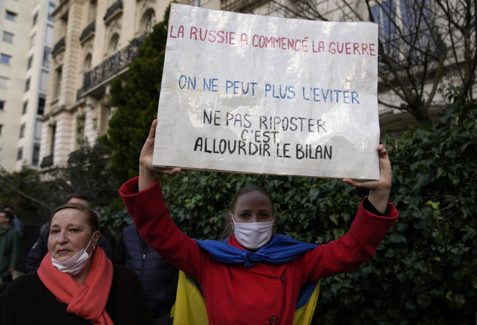 A protestor holds up a sign which reads "Russia started the war, we can no longer avoid it. Not to retaliate is to increase the balance sheet" during a demonstration in front of the Russian embassy in Paris, France, Tuesday, Feb. 22, 2022. World leaders are getting over the shock of Russian President Vladimir Putin ordering his forces into separatist regions of Ukraine and they are focusing on producing as forceful a reaction as possible. Germany made the first big move Tuesday and took steps to halt the process of certifying the Nord Stream 2 gas pipeline from Russia. (AP Photo/Francois Mori)