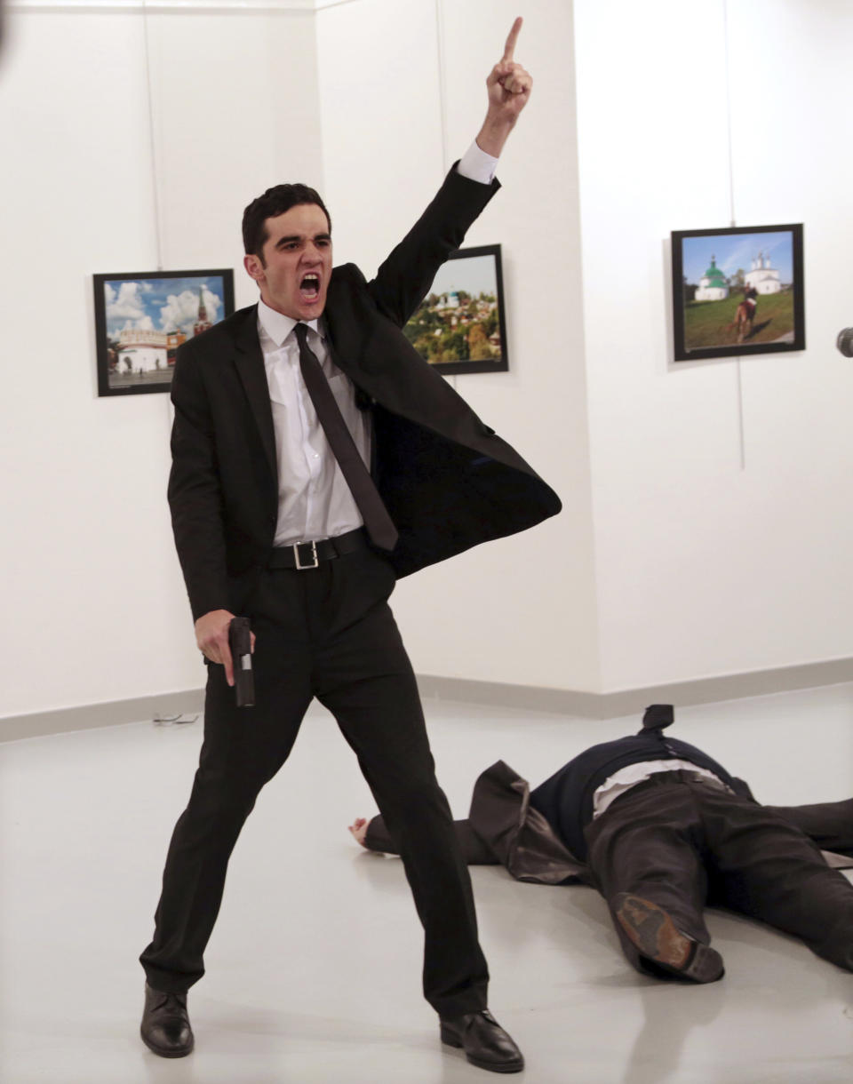 FILE - In this Monday, Dec. 19, 2016 file photo, Mevlut Mert Altintas, an off-duty policeman, shouts after shooting Andrei Karlov, right, the Russian ambassador to Turkey, at an art gallery in Ankara, Turkey. Altintas was killed by police shortly afterwards. A Turkish Court on Tuesday, March 9, 2021 sentenced five people to life prison terms over the assassination of Karlov. Turkish prosecutors concluded that a network led by U.S.-based Muslim cleric Fethullah Gulen was behind Karlov's slaying and charged 28 people, including Gulen, over the killing. (AP Photo/Burhan Ozbilici, File)