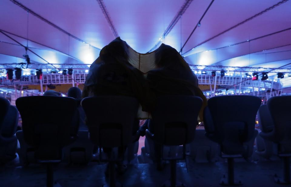 <p>Fans take cover under plastic to shield themselves from the rain as they wait for the start of the closing ceremony for the Summer Olympics at Maracana stadium in Rio de Janeiro, Brazil, Sunday, Aug. 21, 2016. (AP Photo/Mark Humphrey) </p>