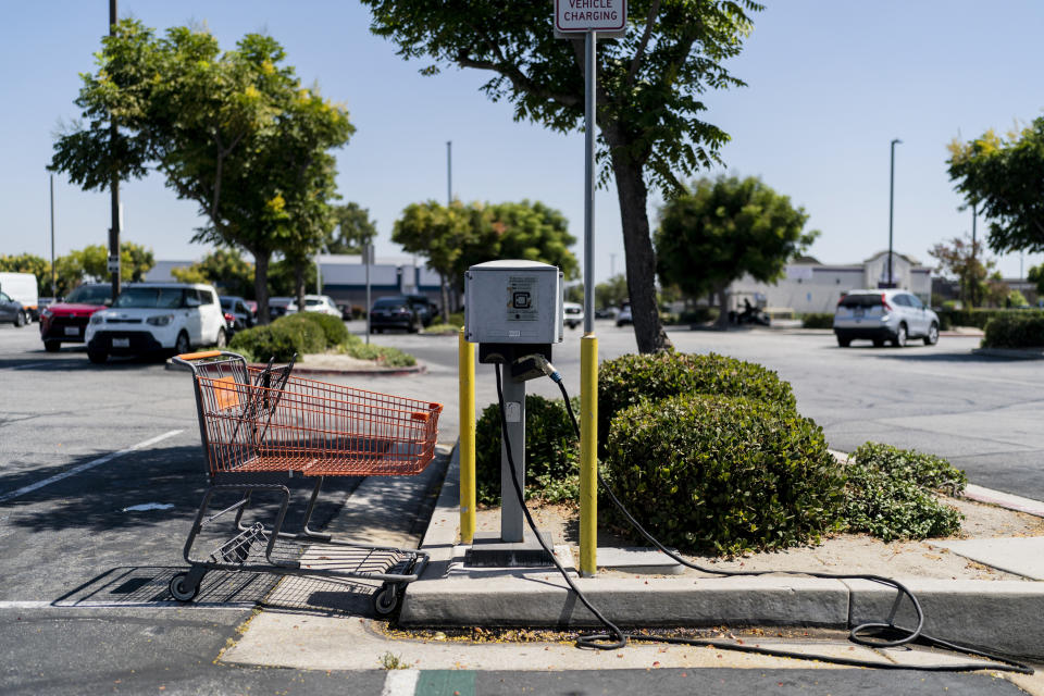 A shopping cart is left in a parking space next to an electric vehicle charger in Downey, Calif., Monday, Aug. 29, 2022. Discounted prices, car-share programs, and a robust network of public charging stations are among the ways California will try to make electric vehicles affordable and convenient for people of all income levels as it phases out the sale of new gas cars by 2035. Advocates for the policy say the switch from gas- to battery-powered cars is a necessary step to reducing pollution in disadvantaged neighborhoods, but that the state make sure those residents can access the cars, too.(AP Photo/Jae C. Hong)