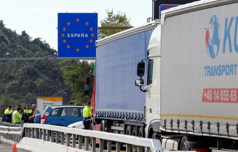 Spanish police officers and drivers stand on the motorway in Le Perthus near the Franco-Spanish border as Catalan demonstrators block the Spanish motorway during Catalonia's general strike