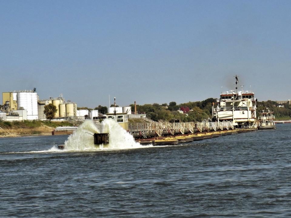 dredge long boat with water shooting out of the ends in mississippi river