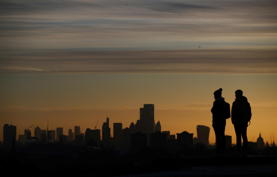 People watch the sun rise behind the city of London financial district and The Shard in London, Britain, December 11, 2019. REUTERS/Hannah McKay