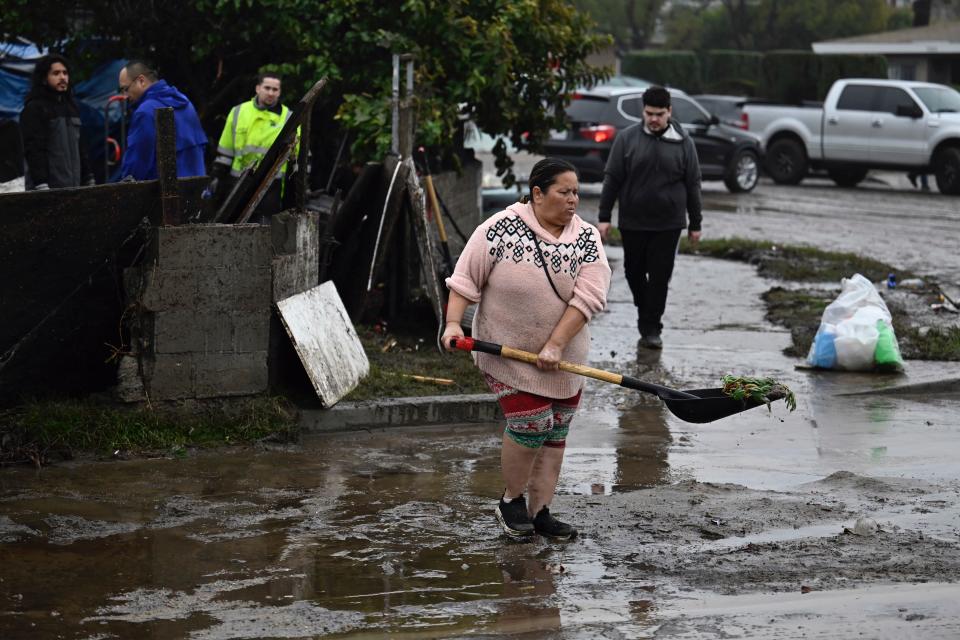 A woman removes debris from floods during a rain storm Monday, Jan. 22, 2024, in San Diego.