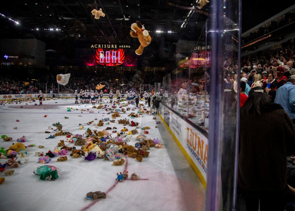The ice fills up with over 7,000 teddy bears and other stuffed toys after a goal is scored by Coachella Valley forward Luke Henman (10) during the third period of their game at Acrisure Arena in Palm Desert, Calif., Friday, Dec. 23, 2022. 