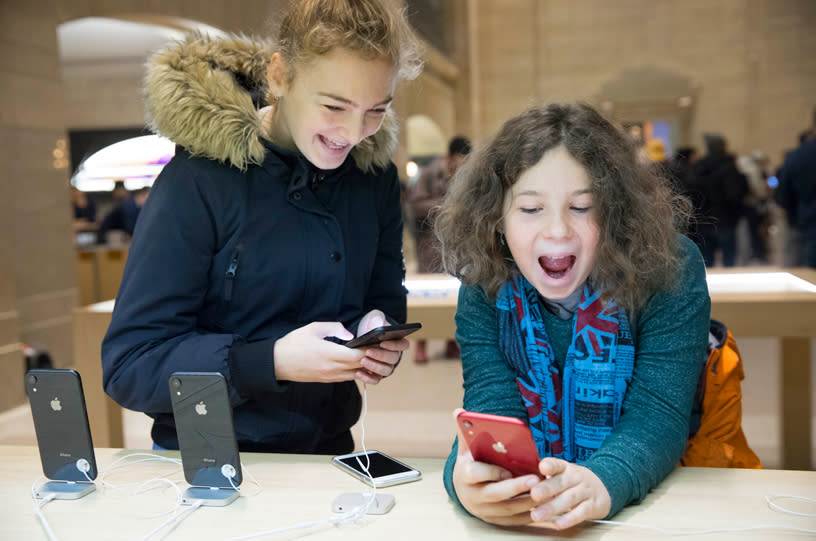 Two girls playing with iPhones in an Apple store.