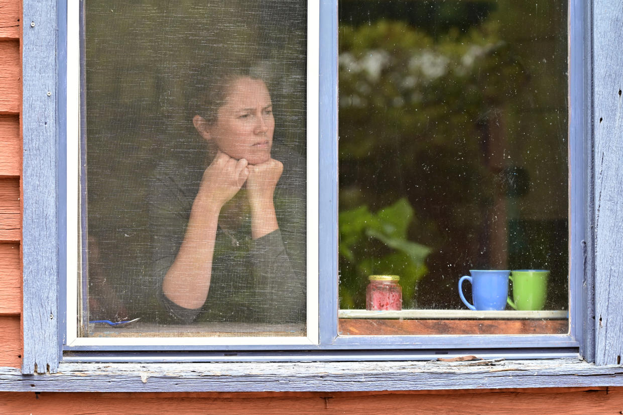 Worried woman looking out kitchen window after interest rate decision.