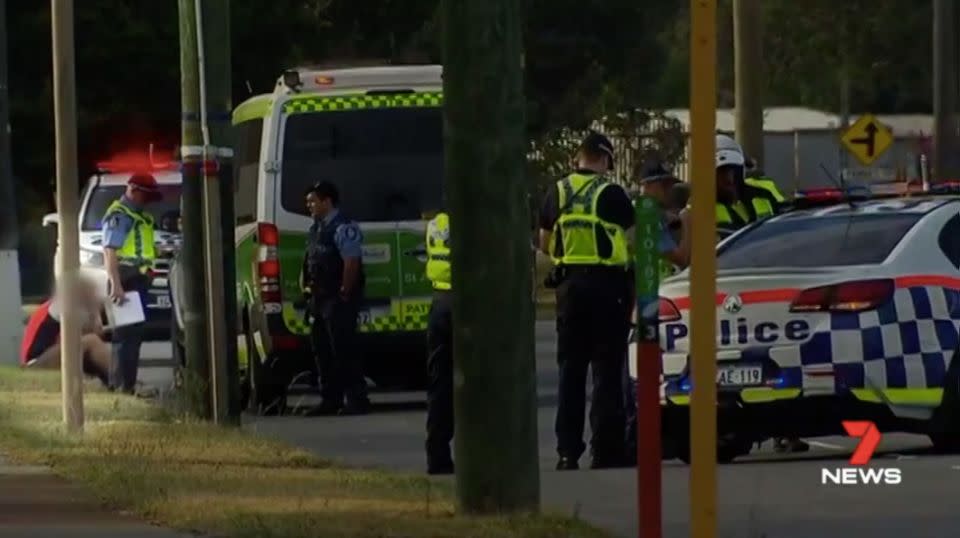 A man sits on the side of the road with his head in his hands as police attend the tragic scene. Source: 7 News