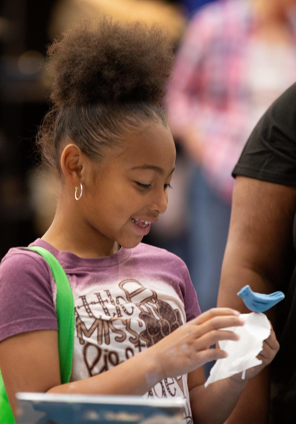 Seven-year-old Alaysia Esparza looks at her new claw bird during the Lubbock Arts Festival, Saturday, April 9, 2022, at Lubbock Memorial Civic Center. Esparza named the bird Coco. 