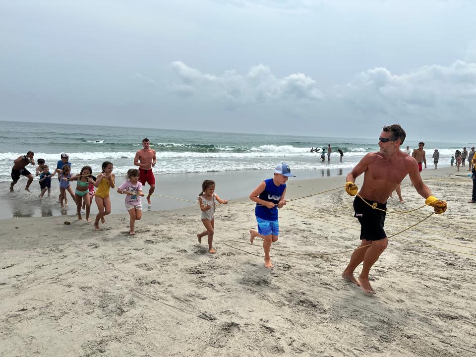 Chief Lifeguard Patrick Murphy leads a charge of children pulling a mock victim from the water with a long rope during Thursday's Water Safety Day.