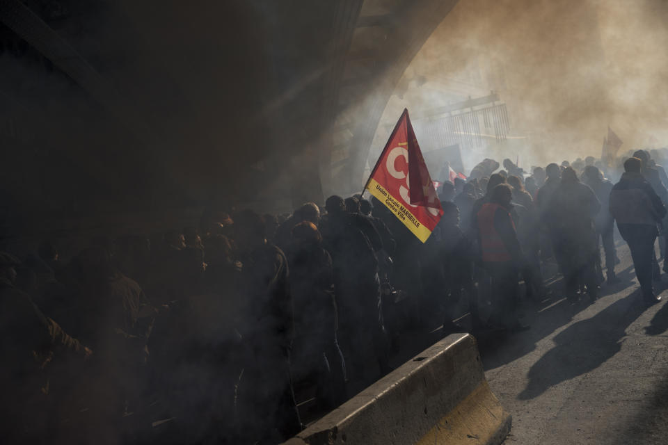 FILE - In this Dec. 10, 2019, file photo, protesters march through smoke from flares at a demonstration during a mass strike in Marseille, southern France. Unions represent less than 10% of salaried workers but have a cozy, if paradoxical, relationship with officialdom that empowers them to block change. (AP Photo/Daniel Cole, File)