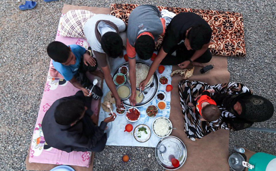 <p>A family breaks their fast on the first day of the Muslim holy month of Ramadan, at al-Khazir camp for the internally displaced, located between Arbil and Mosul, on May 27, 2017. (Photo: Karim Sahib/AFP/Getty Images) </p>