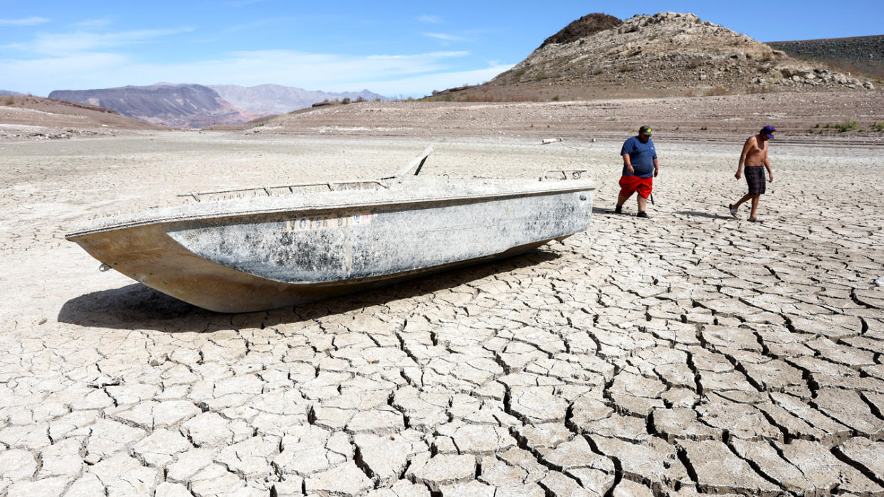 Local residents Derek Diaz, right, and Ornan Valdivia walk near a formerly sunken boat resting on a section of dry lakebed along drought-stricken Lake Mead on Monday.