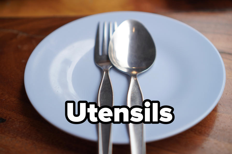 A blue plate with a fork and a spoon resting side by side on a wooden table