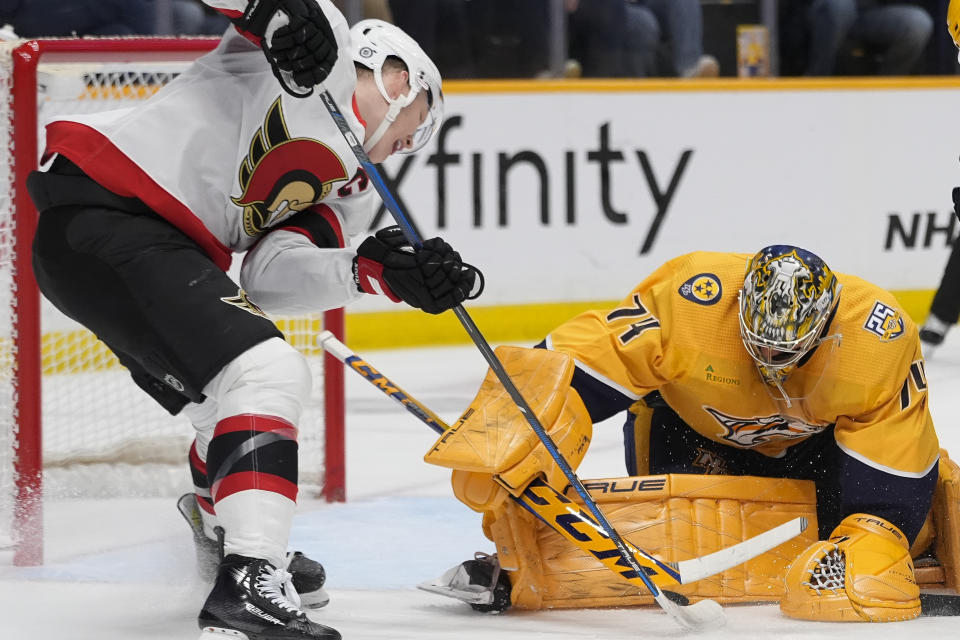 Nashville Predators goaltender Juuse Saros (74) blocks a shot on goal by Ottawa Senators left wing Brady Tkachuk, left, during the first period of an NHL hockey game Tuesday, Feb. 27, 2024, in Nashville, Tenn. (AP Photo/George Walker IV)