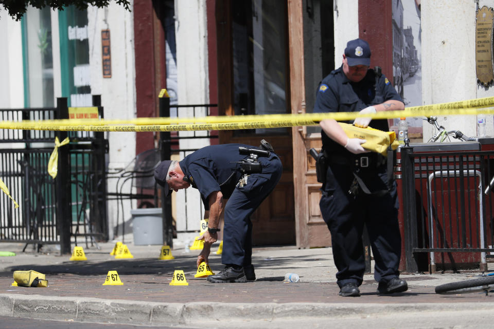 Authorities retrieve evidence markers at the scene of a mass shooting, Sunday, Aug. 4, 2019, in Dayton, Ohio. Multiple people in Ohio have been killed in the second mass shooting in the U.S. in less than 24 hours, and the suspected shooter is also deceased, police said. (AP Photo/John Minchillo)