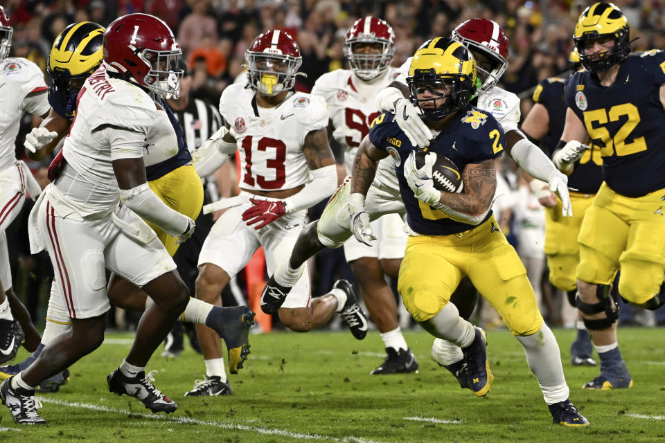 Michigan running back Blake Corum (2) runs in for a touchdown past Alabama defensive back Kool-Aid McKinstry (1) during overtime at the Rose Bowl CFP NCAA semifinal college football game Monday, Jan. 1, 2024, in Pasadena, Calif. (AP Photo/Kyusung Gong)