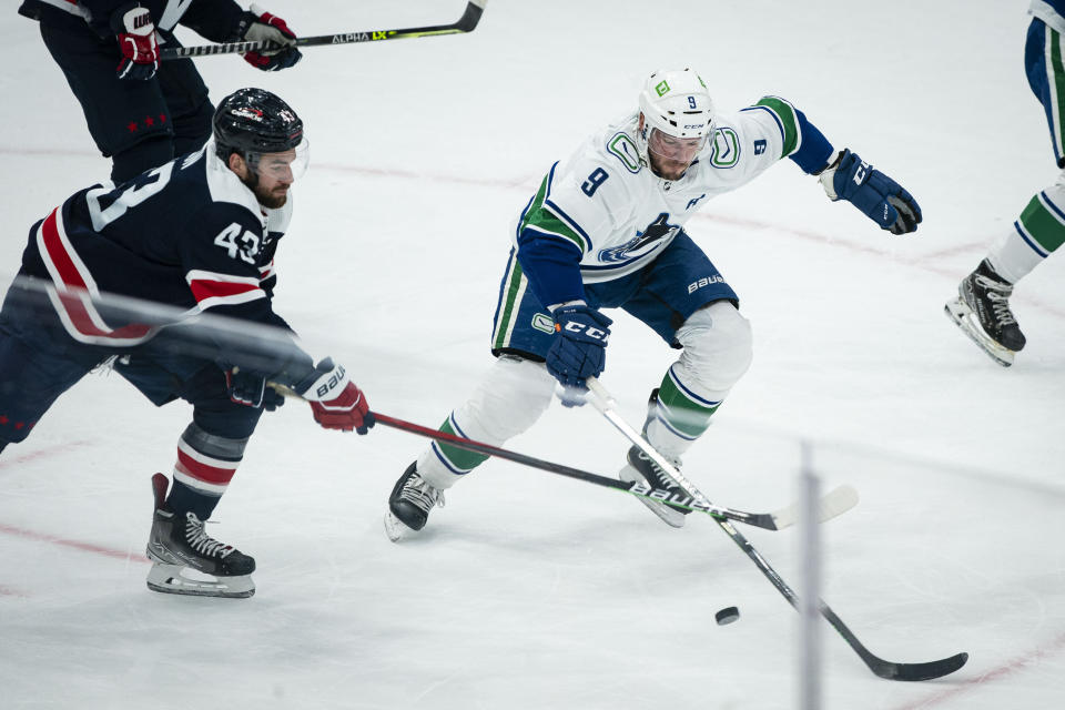 Washington Capitals right wing Tom Wilson (43) moves the puck past Vancouver Canucks center J.T. Miller (9) during the first period of an NHL hockey game against the Vancouver Canucks, Sunday, Jan. 16, 2022, in Washington. (AP Photo/Al Drago)