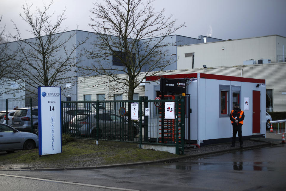 A security guard stands at the entrance of the Novasep factory in Seneffe, Belgium, Friday, Jan. 29, 2021. Amid a dispute over expected shortfalls, the European Union is looking at legal ways to guarantee the delivery of all the COVID-19 vaccine doses it bought from AstraZeneca and other drugmakers as regulators are set to consider approving the Anglo-Swedish company's vaccine for use in the 27-nation EU. (AP Photo/Francisco Seco)
