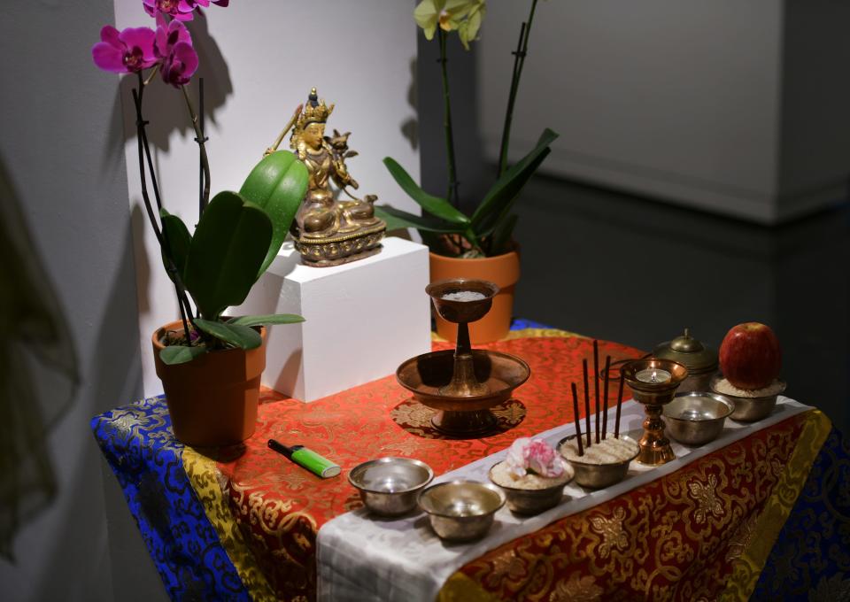 A  Buddhist Tibetan altar has bowls of fresh water, rice, flowers, an apple and other meaningful items placed in honor.