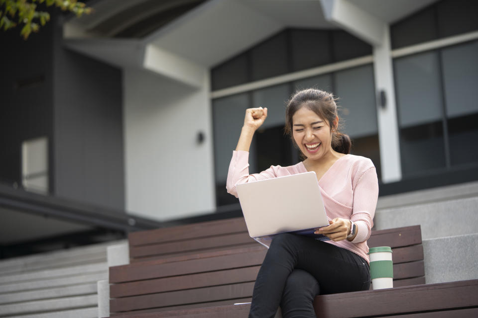 Excited student reading good news on line in a smart laptop