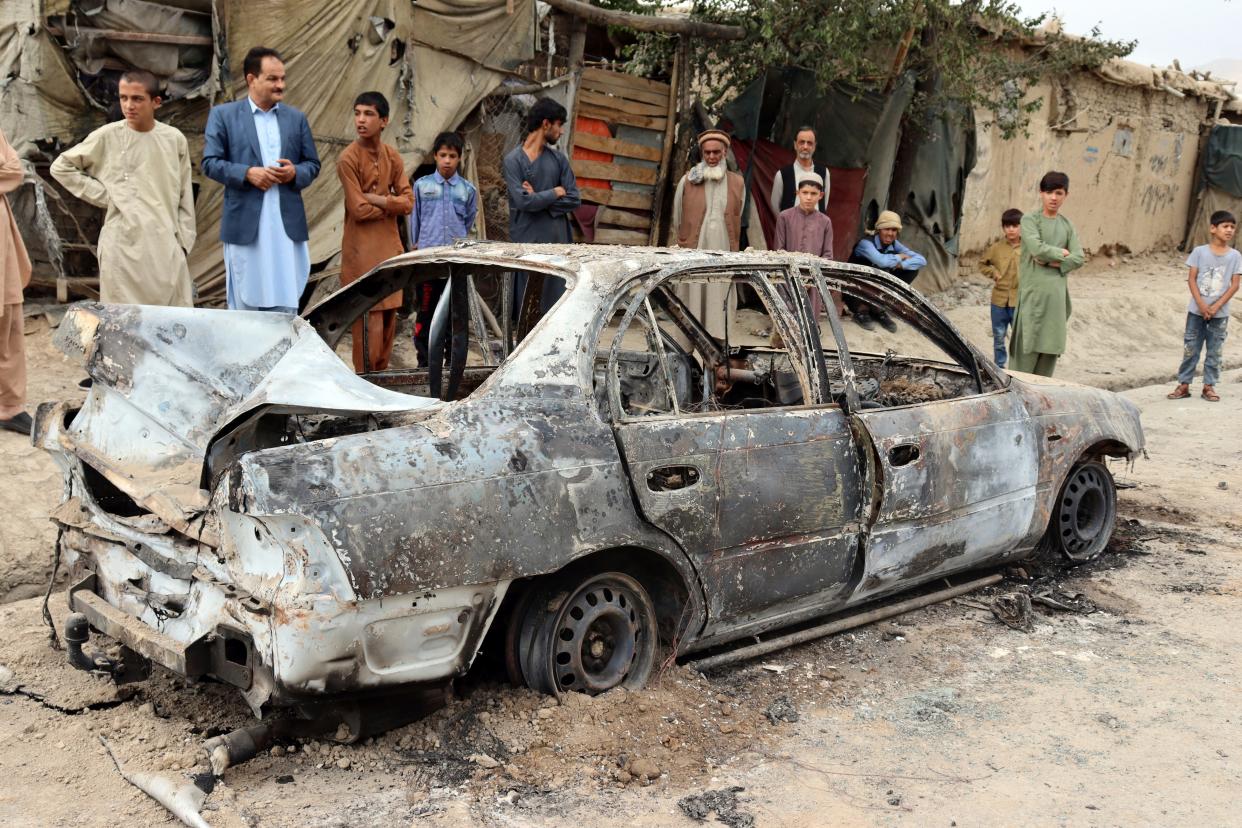 Locals look at a car destroyed in a rocket attack in Kabul, Afghanistan, in August 2021. Rockets struck a neighborhood near the international airport amid the U.S. withdrawal. After a 20-year war, the U.S. pulled out all troops and the Taliban took over again.