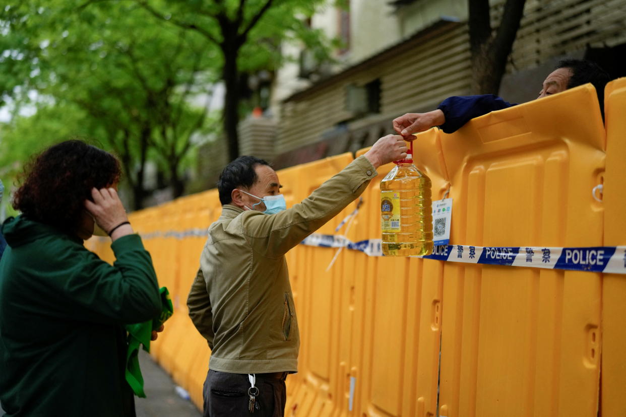 People pass edible oil over the barriers at a street market under lockdown amid the coronavirus disease (COVID-19) pandemic, in Shanghai, China April 13, 2022. REUTERS/Aly Song