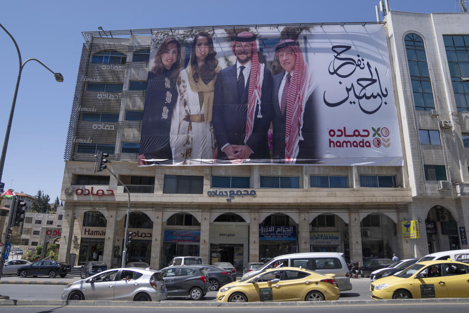 A poster with pictures of, from right, King Abdullah II, Crown Prince Hussein, Saudi architect Rajwa Alseif and Queen Rania, is hanged at the front of a building in the capital Amman, Jordan, Wednesday, May 31, 2023. Crown Prince Hussein and Saudi architect Rajwa Alseif are to be married on Thursday at a palace wedding in Jordan, a Western-allied monarchy that has been a bastion of stability for decades as Middle East turmoil has lapped at its borders. (AP Photo/Nasser Nasser)